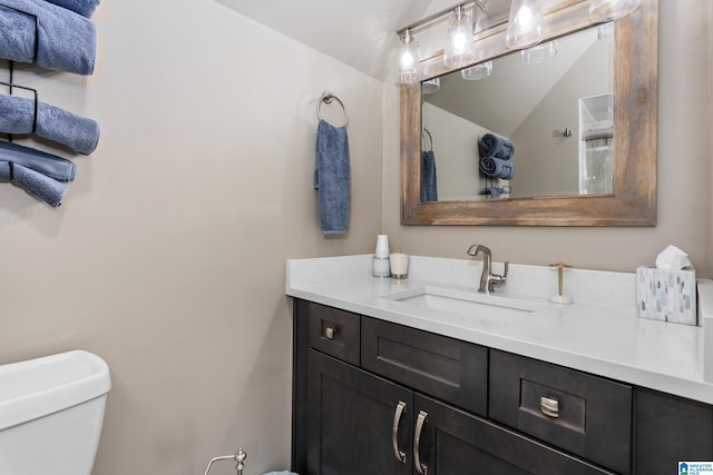 bathroom with vanity, toilet, and vaulted ceiling