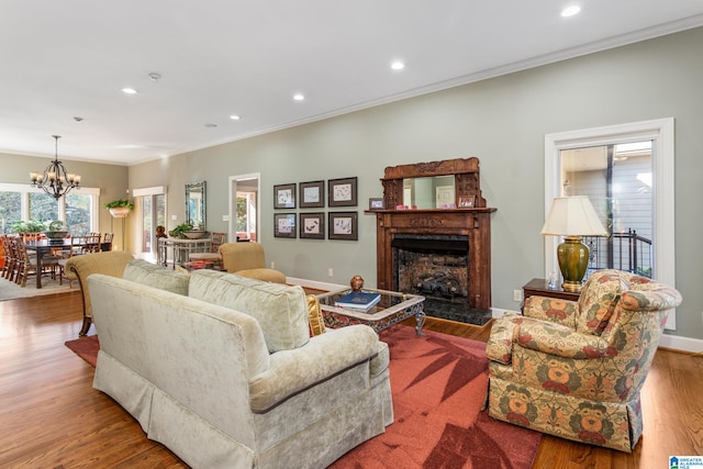 living room with a fireplace, light hardwood / wood-style flooring, ornamental molding, and a notable chandelier