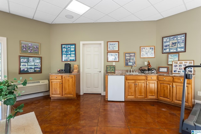 kitchen with light stone countertops, a drop ceiling, dark tile patterned floors, sink, and dishwasher