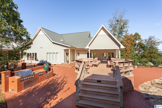 back of property with an outdoor kitchen and a deck