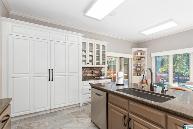 kitchen with dishwasher, sink, dark stone countertops, white cabinets, and ornamental molding