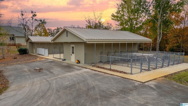 1001 Kingsway Dr, Anniston, AL 36207 - view of front facade featuring an exterior structure, driveway, an outdoor structure, metal roof, and stucco siding