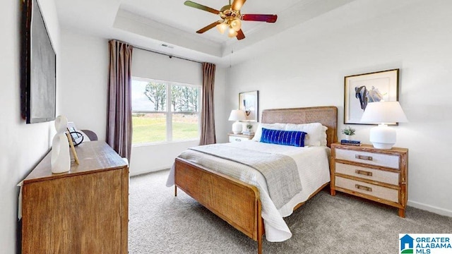 bedroom with a tray ceiling, ceiling fan, crown molding, and light colored carpet