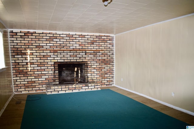 unfurnished living room featuring crown molding, a fireplace, and brick wall