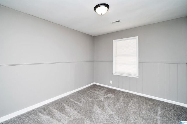 empty room featuring carpet and wooden walls