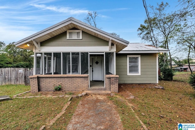 bungalow-style home featuring a sunroom and a front yard