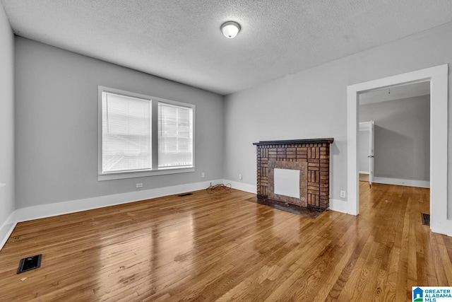 unfurnished living room featuring a fireplace, a textured ceiling, and hardwood / wood-style flooring