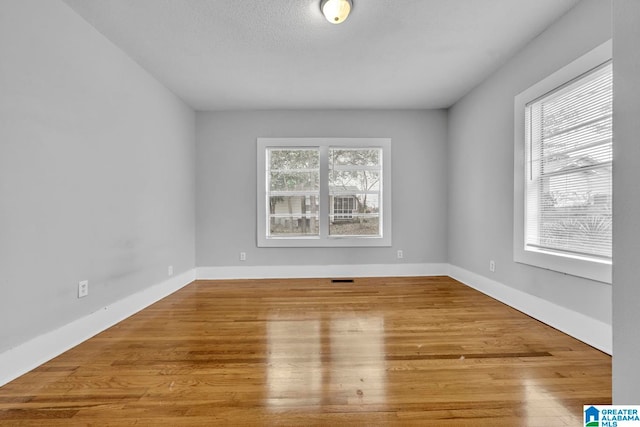 unfurnished room featuring hardwood / wood-style floors and a textured ceiling