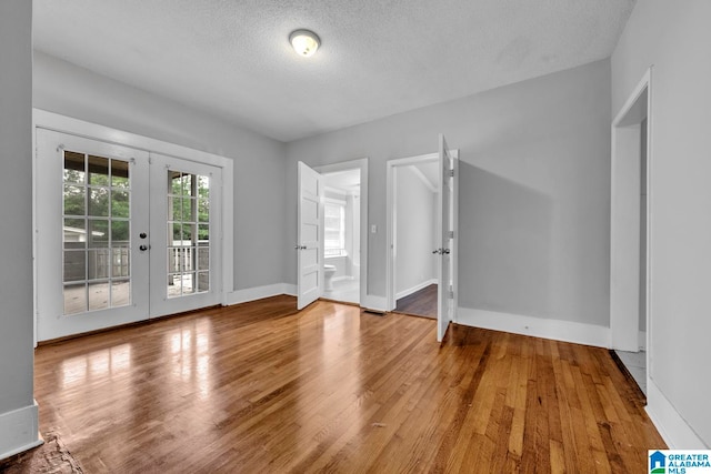 unfurnished room with hardwood / wood-style floors, a textured ceiling, and french doors