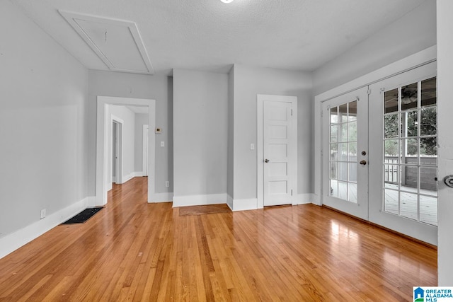 unfurnished room featuring french doors, a textured ceiling, and light wood-type flooring