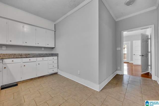 kitchen with white cabinetry, a textured ceiling, and ornamental molding