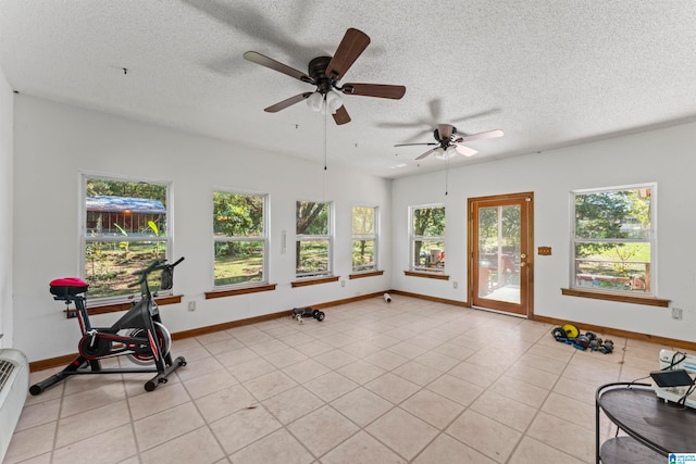 workout area featuring light tile patterned floors, a textured ceiling, a wealth of natural light, and ceiling fan