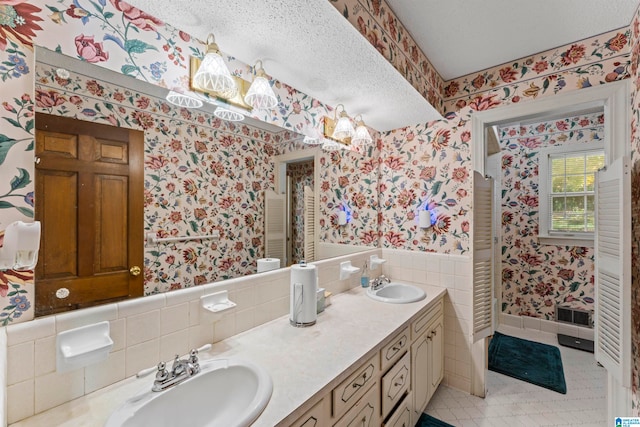 bathroom with tile patterned flooring, vanity, a textured ceiling, and tile walls