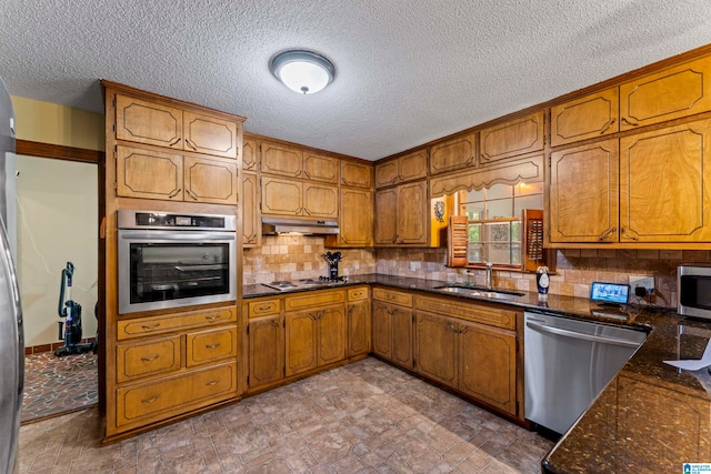 kitchen featuring appliances with stainless steel finishes, backsplash, a textured ceiling, and sink