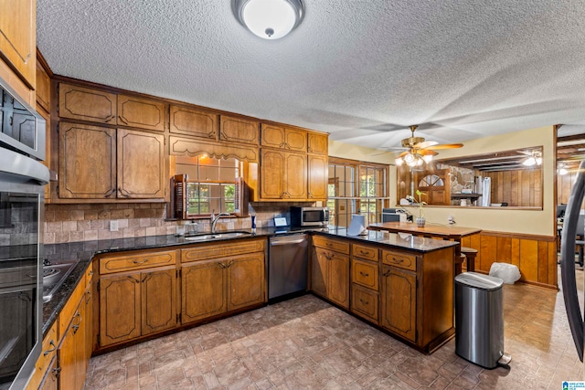 kitchen with plenty of natural light, decorative backsplash, kitchen peninsula, and appliances with stainless steel finishes