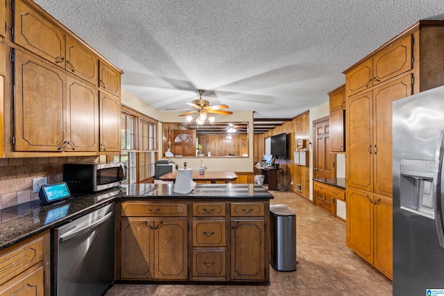 kitchen with kitchen peninsula, wood walls, a textured ceiling, and appliances with stainless steel finishes