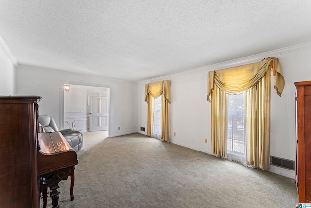 sitting room featuring a textured ceiling, light colored carpet, and ornamental molding