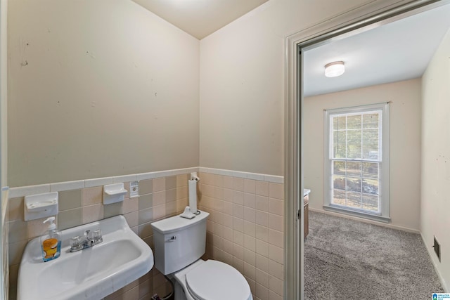 bathroom with toilet, tile walls, and sink