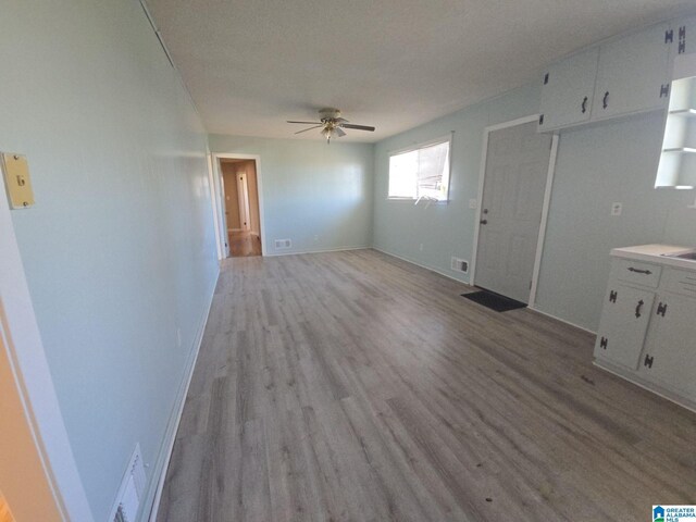 unfurnished living room with baseboards, light wood-style flooring, visible vents, and a ceiling fan