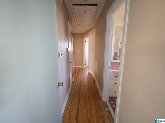 corridor with attic access, baseboards, and wood finished floors