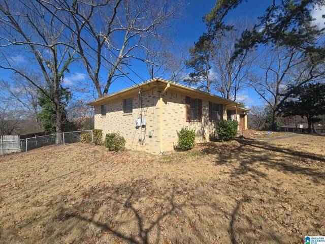 view of property exterior featuring brick siding and fence