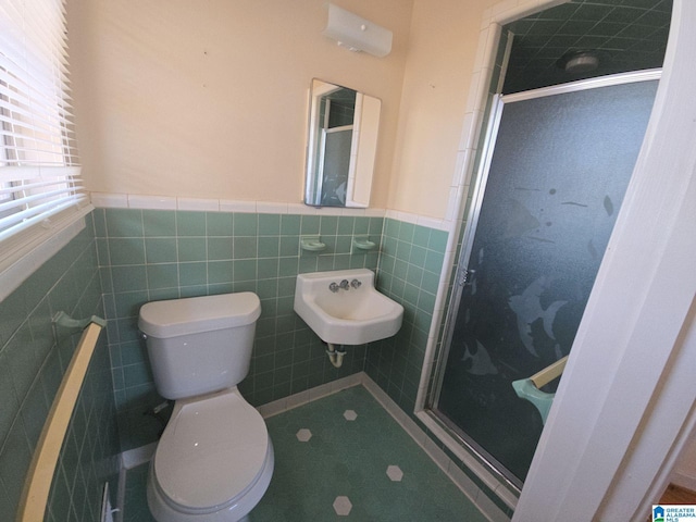 full bath with tile walls, toilet, wainscoting, a sink, and a shower stall