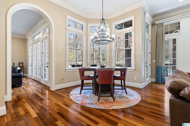 dining room with dark hardwood / wood-style flooring, ornamental molding, french doors, and an inviting chandelier