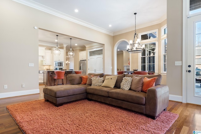 living room with light wood-type flooring, an inviting chandelier, and ornamental molding