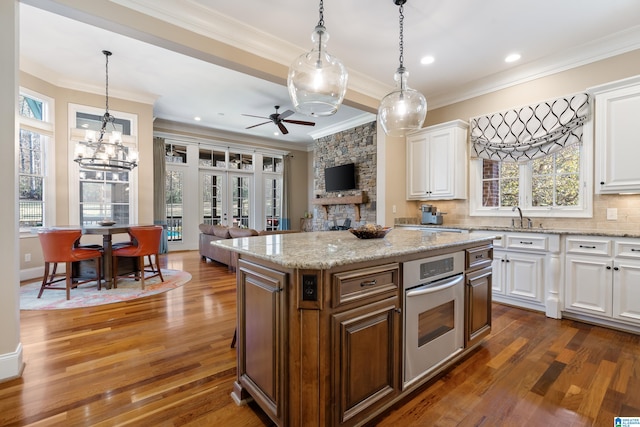 kitchen featuring stainless steel oven, white cabinets, hanging light fixtures, and dark hardwood / wood-style floors