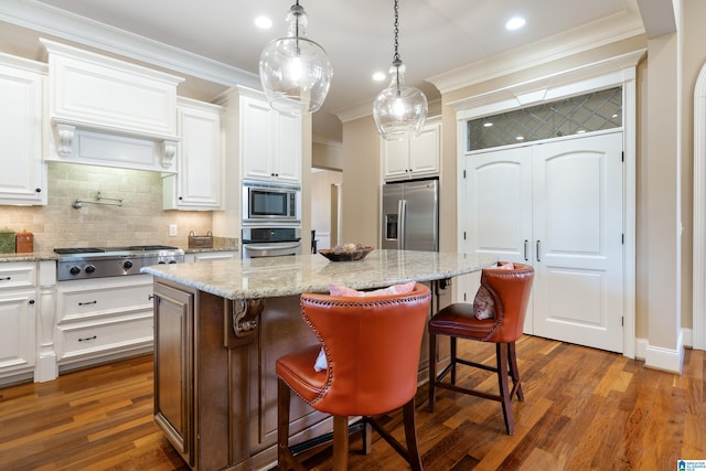 kitchen featuring a kitchen breakfast bar, a kitchen island, white cabinetry, and stainless steel appliances