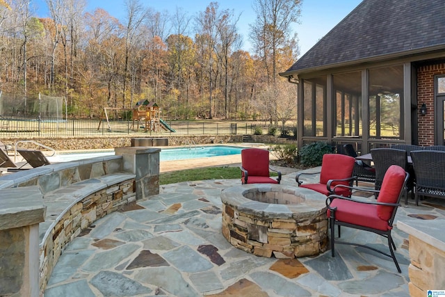 view of patio featuring a playground, a fire pit, and a fenced in pool