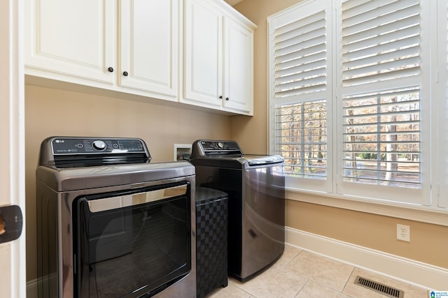 laundry room featuring cabinets, washing machine and dryer, and light tile patterned floors