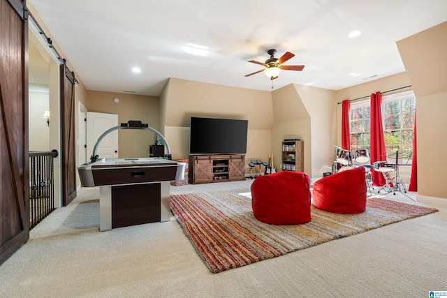 living room featuring ceiling fan, a barn door, and light carpet