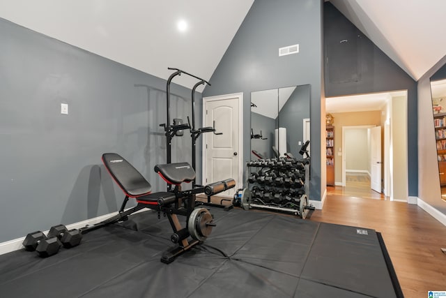 exercise room featuring hardwood / wood-style floors and high vaulted ceiling