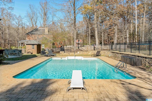 view of swimming pool with a diving board and a patio