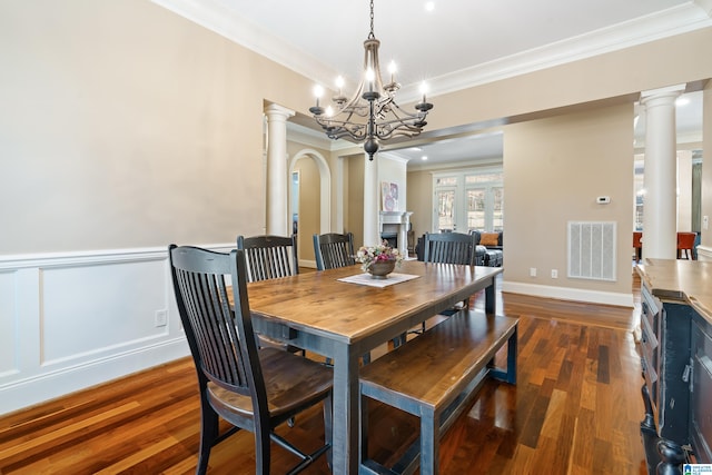 dining space with dark hardwood / wood-style floors, crown molding, decorative columns, and a notable chandelier