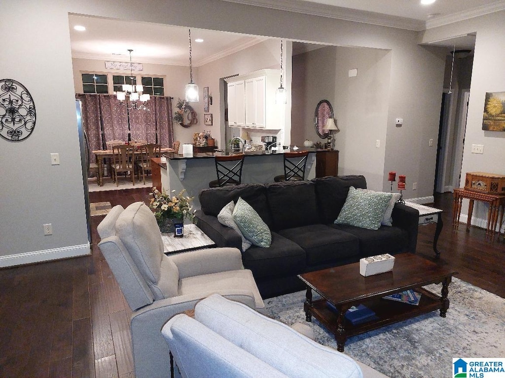 living room featuring dark hardwood / wood-style flooring, ornamental molding, and a chandelier