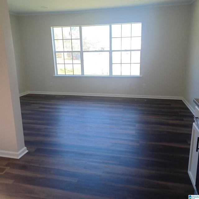 empty room with dark wood-type flooring and ornamental molding