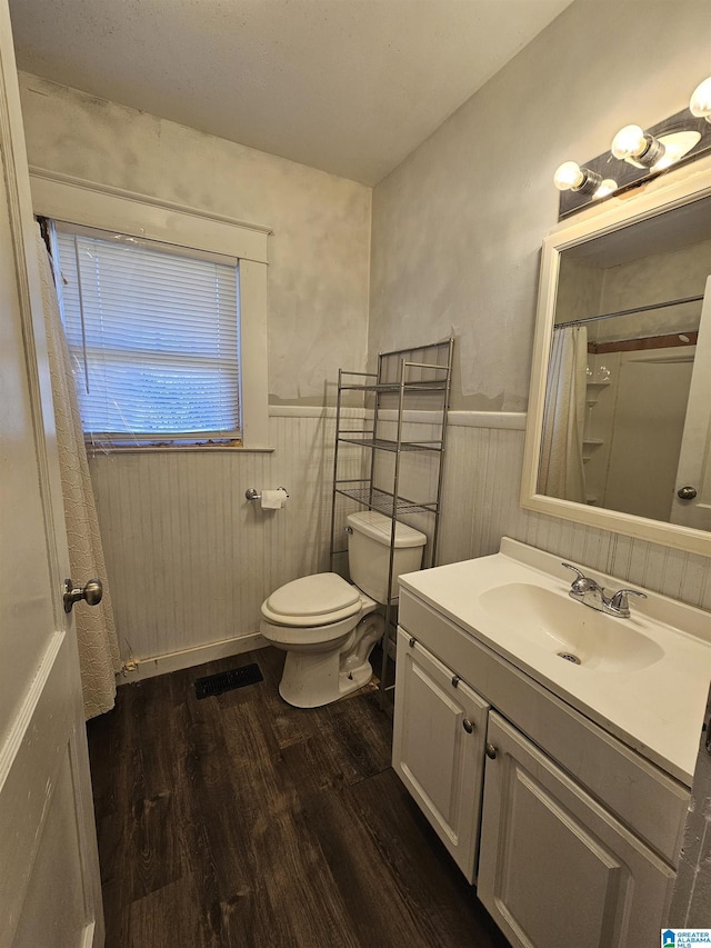 bathroom with a shower with curtain, vanity, wooden walls, hardwood / wood-style flooring, and toilet