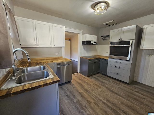 kitchen with butcher block countertops, sink, white cabinetry, and stainless steel appliances