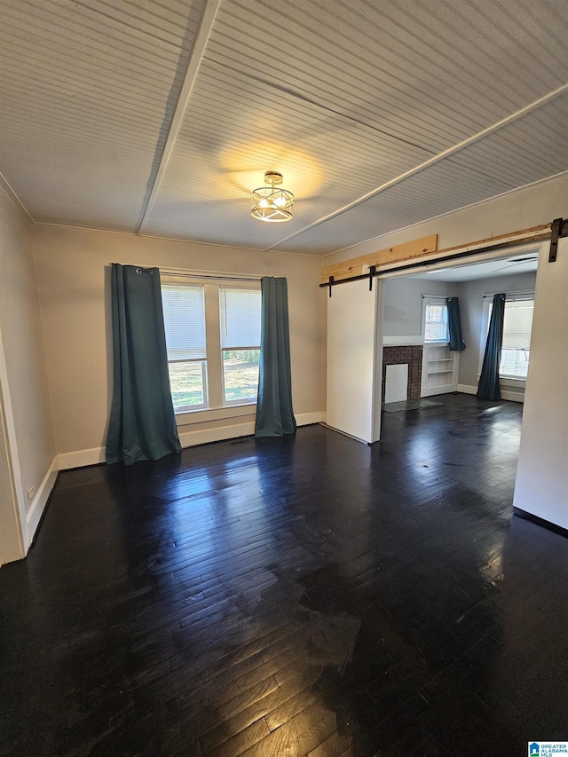 unfurnished room with dark hardwood / wood-style floors and a barn door