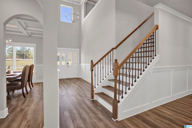 foyer featuring coffered ceiling, crown molding, wood-type flooring, an inviting chandelier, and beamed ceiling