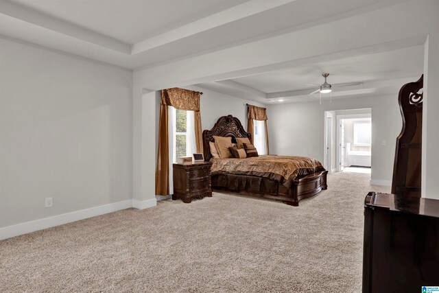 carpeted bedroom featuring a tray ceiling and ceiling fan