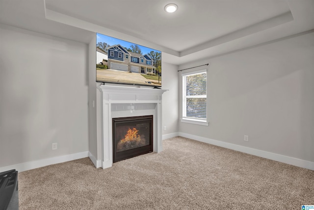 unfurnished living room with a tray ceiling and carpet floors