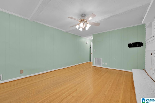 empty room with light wood-type flooring, wooden walls, ceiling fan, and ornamental molding