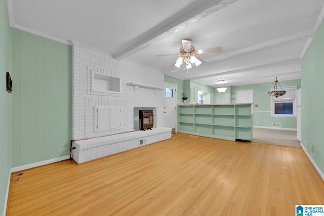 unfurnished living room with a fireplace, a textured ceiling, ceiling fan, hardwood / wood-style flooring, and beamed ceiling