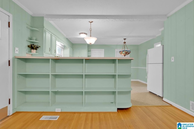 kitchen with kitchen peninsula, light hardwood / wood-style floors, crown molding, white fridge, and hanging light fixtures