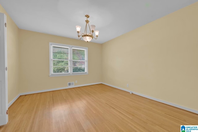 empty room with light wood-type flooring and an inviting chandelier