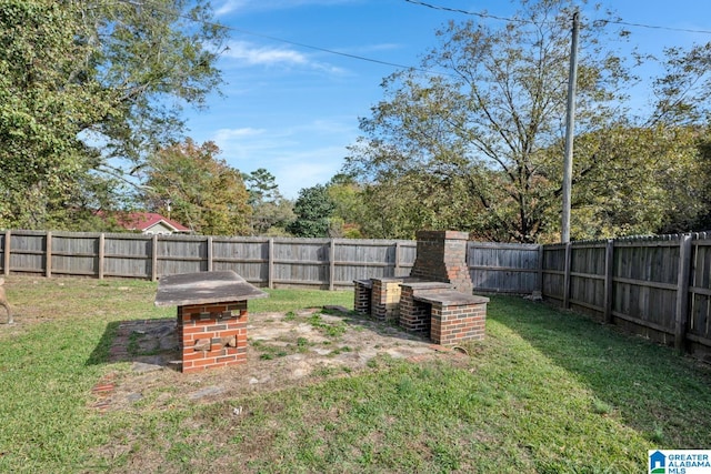 view of yard with an outdoor brick fireplace