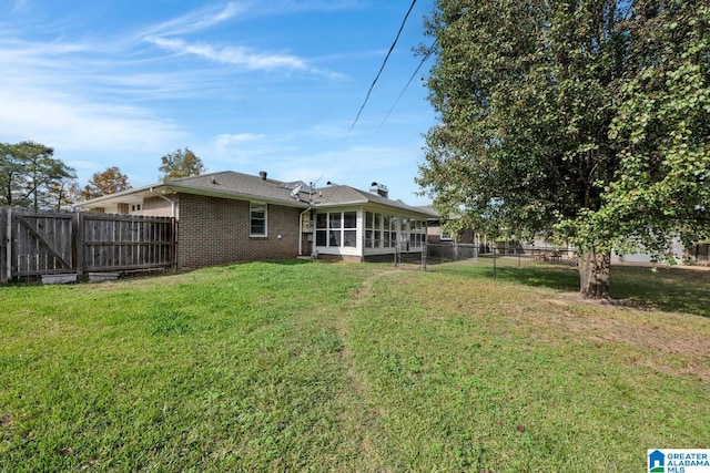 back of property featuring a lawn and a sunroom